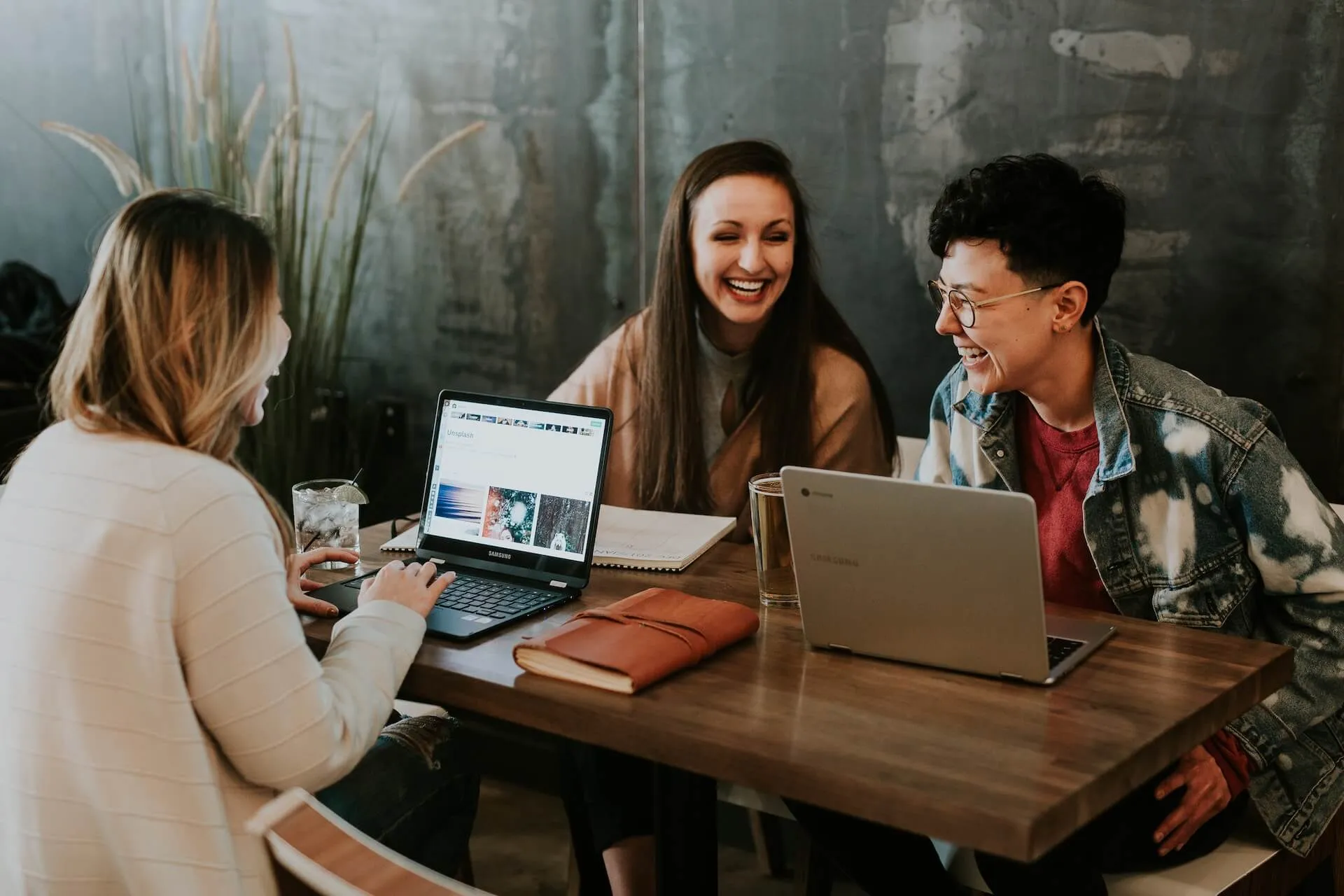 three women laughing at a networking event in a cafe